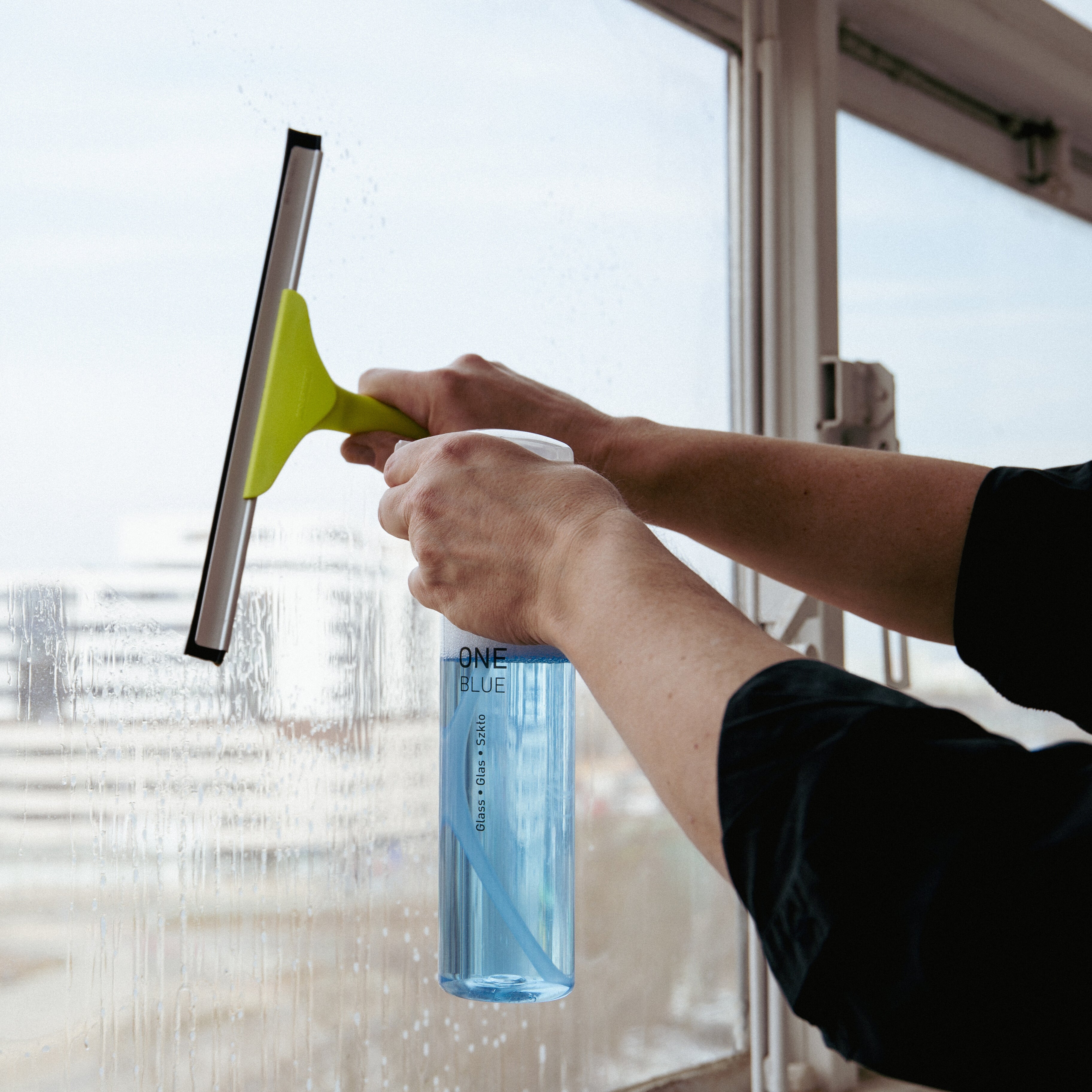 Cleaning window with One Blue glass cleaner and window squeegee